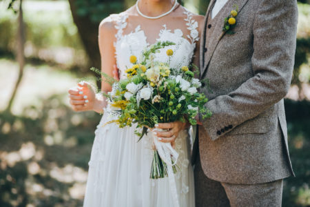 Bride and groom dressed in gray with yellow flower accents