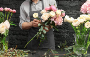 Male florist arranging pink and white flowers at the bar.