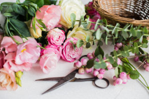 Pink flowers, scissors, and basket for DIY flower arrangement.