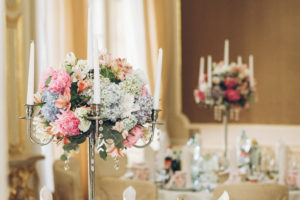pink and blue flowers arranged on top of a silver candelabra
