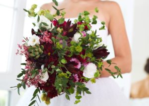 Dramatic-and-wild-bridal-bouquet-with-burgundy-and-dark-pink-blooms-with-a-lot-of-greenery