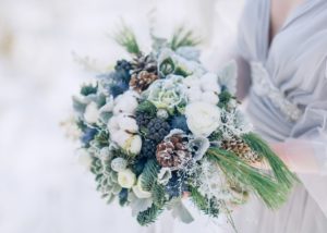 Winter bridal bouquet with white booms pincones and blue berries