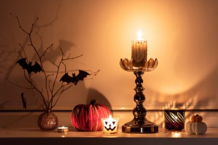 Halloween themed decorations with pumpkins and lit candles on a window sill inside at night